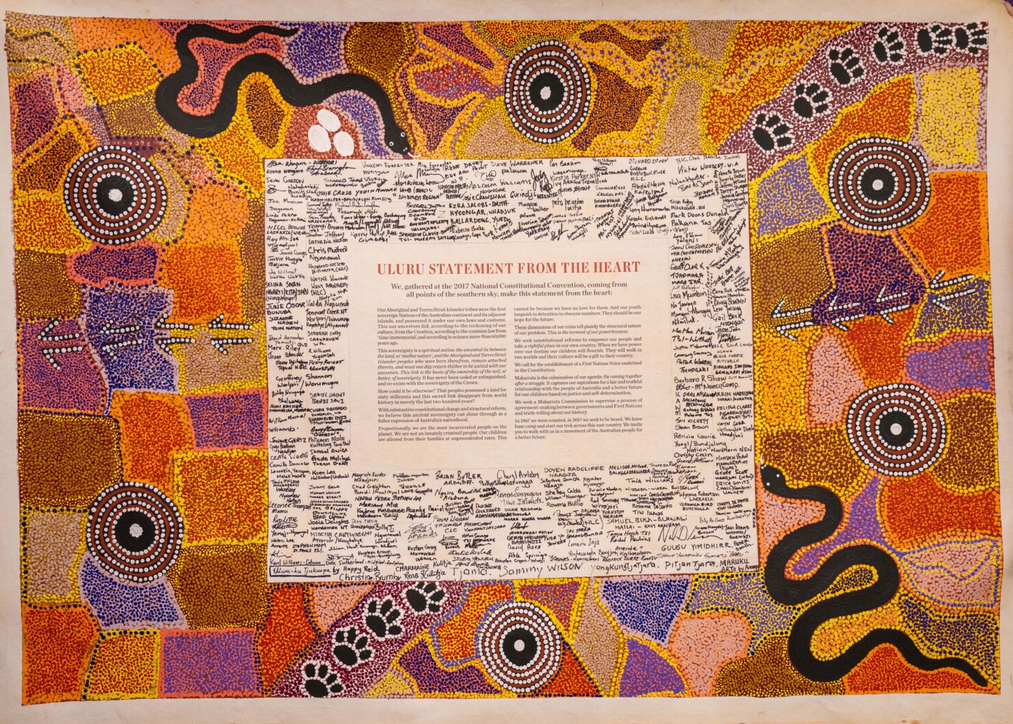ULURU STATEMENT FROM THE HEART surrounded by dot artwork and signed by First Nations and with the following words. "We, gathered at the 2017 National Constitutional Convention, coming from all points of the southern sky, make this statement from the heart: Our Aboriginal and Torres Strait Islander tribes were the first sovereign Nations of the Australian continent and its adjacent islands, and possessed it under our own laws and customs. This our ancestors did, according to the reckoning of our culture, from the Creation, according to the common law from ‘time immemorial’, and according to science more than 60,000 years ago. This sovereignty is a spiritual notion: the ancestral tie between the land, or ‘mother nature’, and the Aboriginal and Torres Strait Islander peoples who were born therefrom, remain attached thereto, and must one day return thither to be united with our ancestors. This link is the basis of the ownership of the soil, or better, of sovereignty. It has never been ceded or extinguished, and co-exists with the sovereignty of the Crown. How could it be otherwise? That peoples possessed a land for sixty millennia and this sacred link disappears from world history in merely the last two hundred years? With substantive constitutional change and structural reform, we believe this ancient sovereignty can shine through as a fuller expression of Australia’s nationhood. Proportionally, we are the most incarcerated people on the planet. We are not an innately criminal people. Our children are aliened from their families at unprecedented rates. This cannot be because we have no love for them. And our youth languish in detention in obscene numbers. They should be our hope for the future. These dimensions of our crisis tell plainly the structural nature of our problem. This is the torment of our powerlessness. We seek constitutional reforms to empower our people and take a rightful place in our own country. When we have power over our destiny our children will flourish. They will walk in two worlds and their culture will be a gift to their country. We call for the establishment of a First Nations Voice enshrined in the Constitution. Makarrata is the culmination of our agenda: the coming together after a struggle. It captures our aspirations for a fair and truthful relationship with the people of Australia and a better future for our children based on justice and self-determination. We seek a Makarrata Commission to supervise a process of agreement-making between governments and First Nations and truth-telling about our history. In 1967 we were counted, in 2017 we seek to be heard. We leave base camp and start our trek across this vast country. We invite you to walk with us in a movement of the Australian people for a better future."