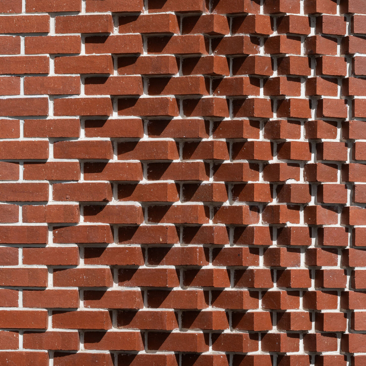 Detail of extruded heritage red brickwork that provides a dynamic pattern inspired by a basketball game's rhythm. The bricks appear to 'ripple' with the play of light and shadow on the building.